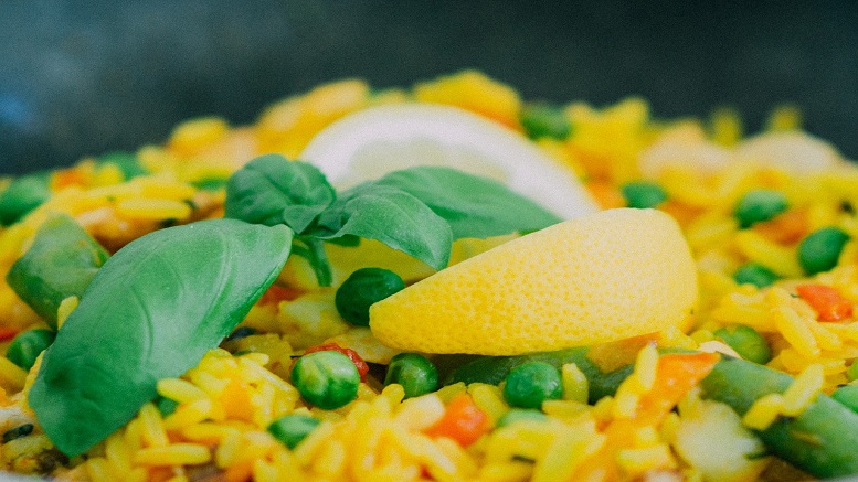 Close up picture of paella with lemon on top