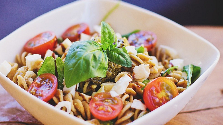 Bowl of tuna pasta salad with tomatoes and basil